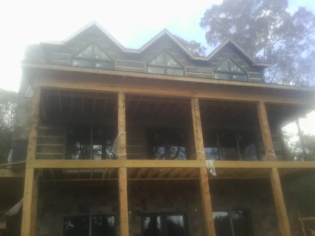Dormers and porch framing on a large log home under construction — Roof Coating work by our crew in Porum