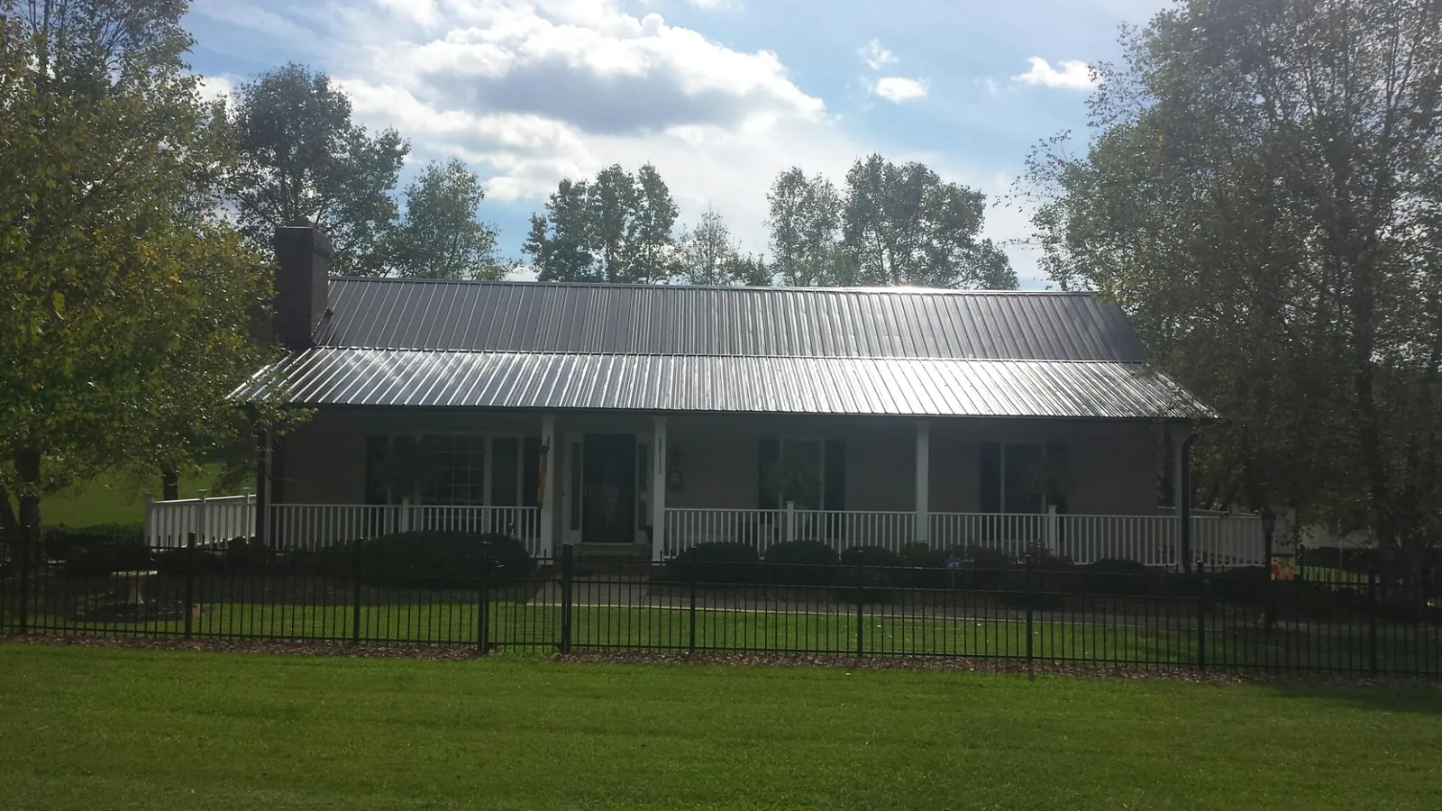Gray metal roof on a brick ranch with a full width front porch — Gutter Guard Installation work by our crew in Porum