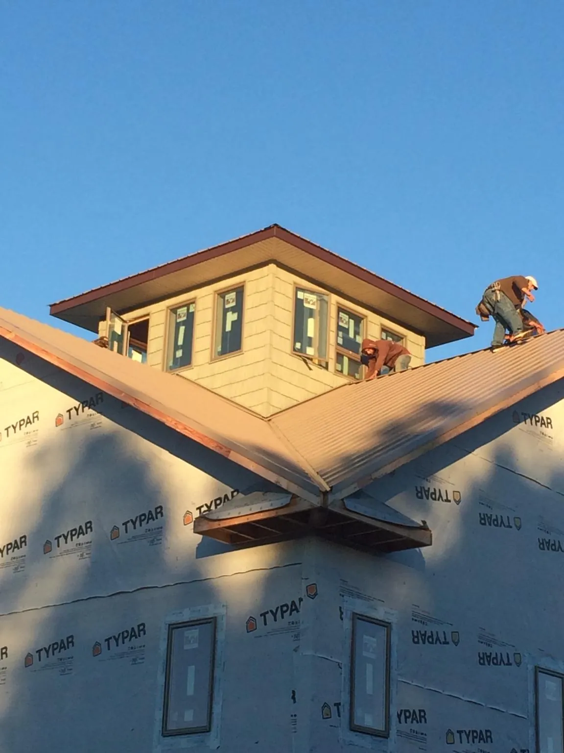 Roofers working around a rooftop cupola on a new metal roof at sunset — Roof Waterproofing in Porum by Roofing Brothers